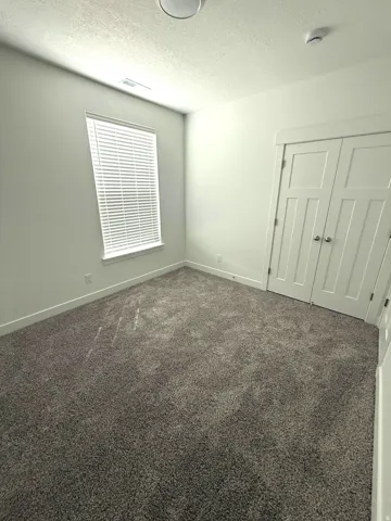 Neutral-toned carpet flooring, a window with blinds, and double panel doors