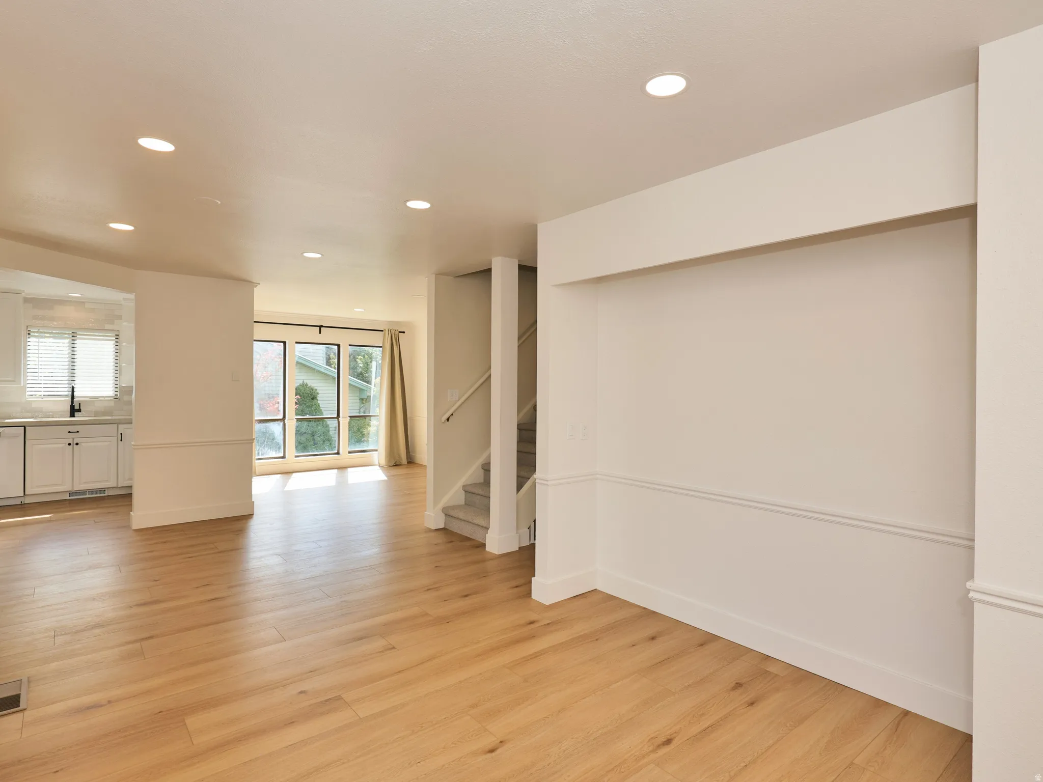 Recessed lighting illuminates wood-finish flooring