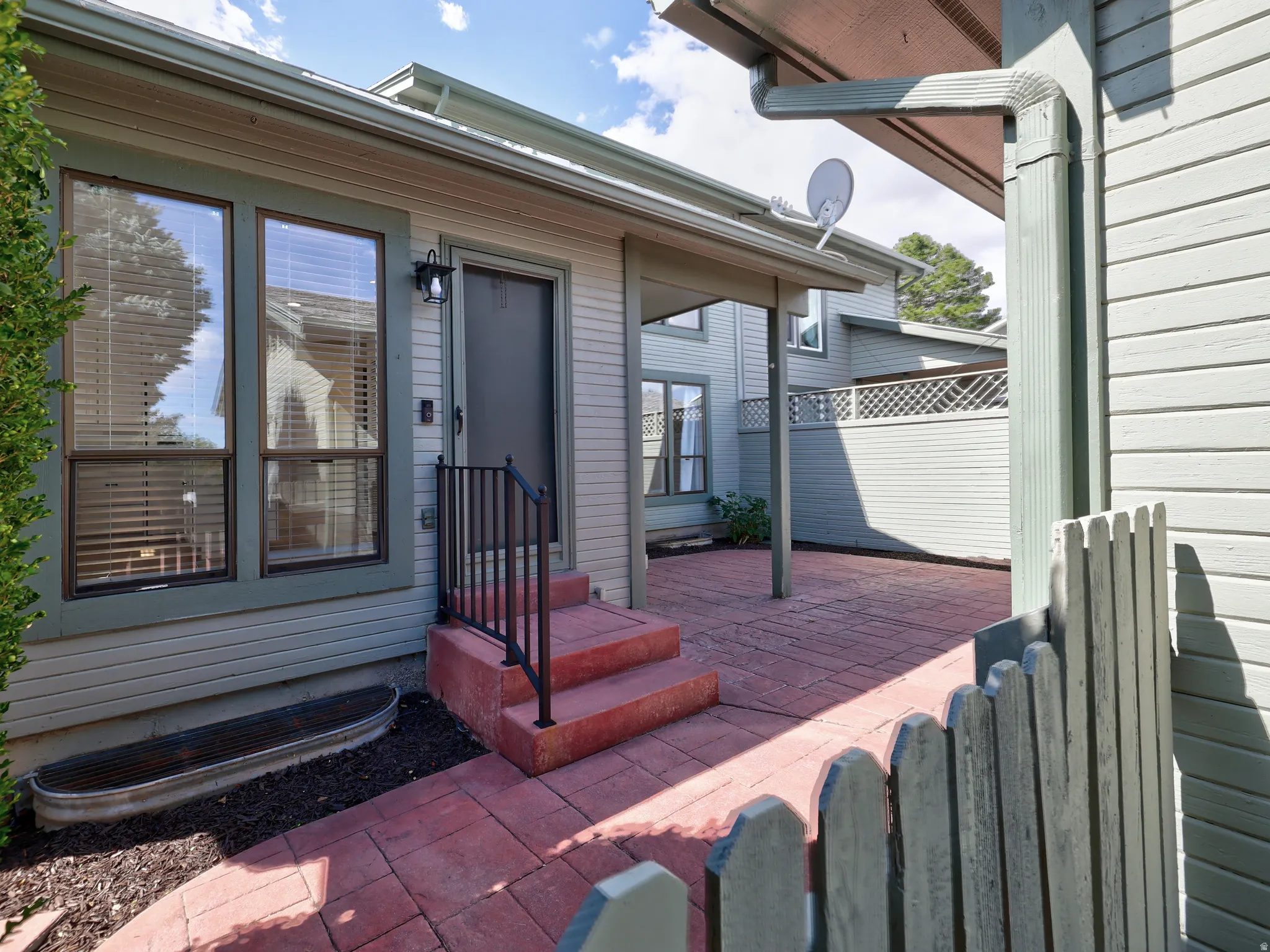 Private outdoor patio featuring red brick pavers and a partial privacy fence