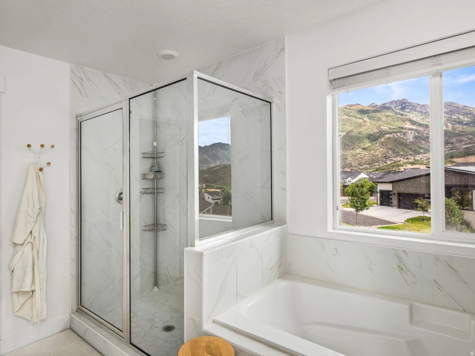 Spacious bathroom featuring a built-in tub, a glass-enclosed shower with tiled walls, and a large window