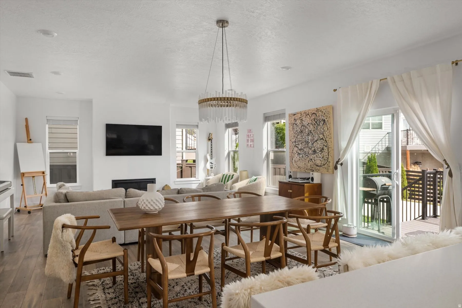 Open-concept living space with a dining area, a linear fireplace, and wood-finish flooring