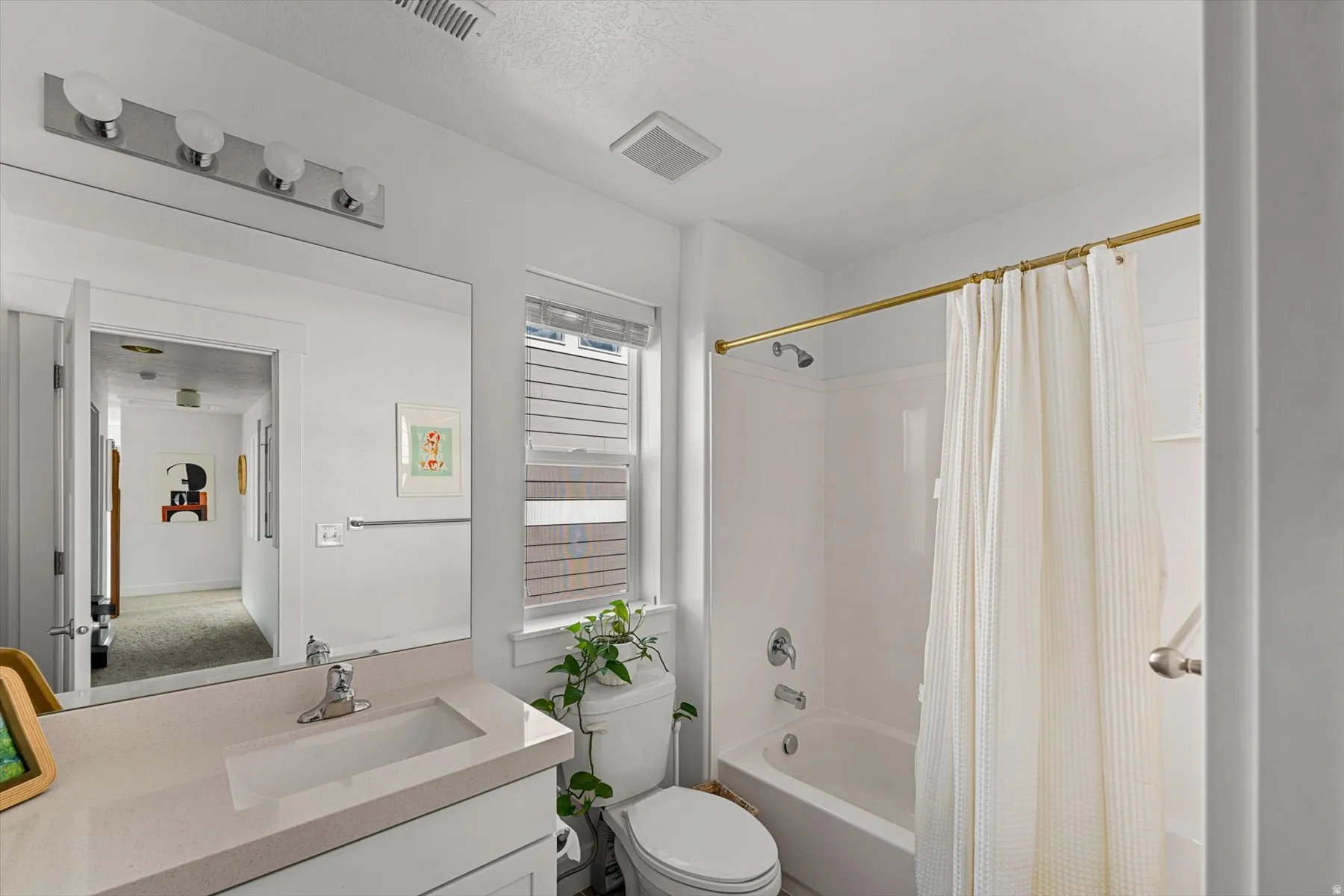 White vanity with an integrated rectangular sink, large frameless mirror, and a four-bulb vanity light fixture