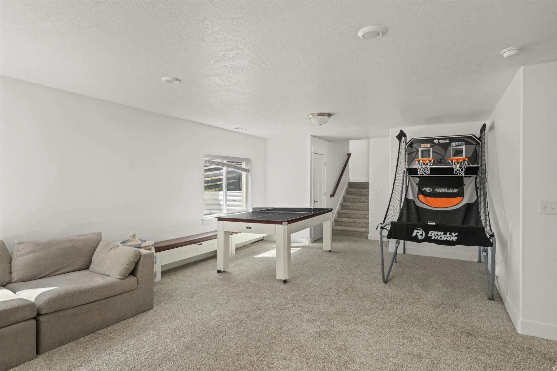 Recessed lighting illuminates a spacious room featuring light-toned carpeting