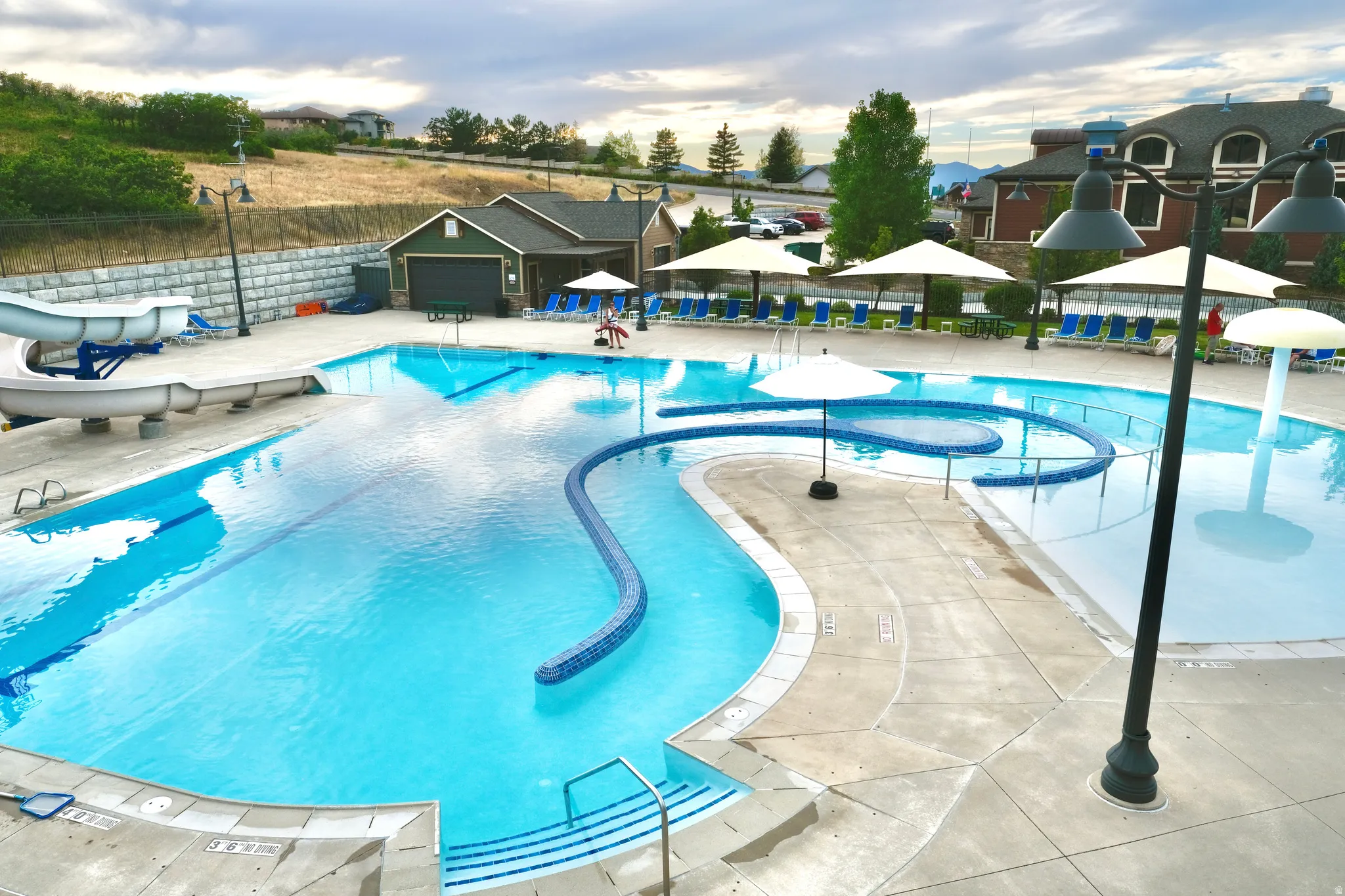 Expansive swimming facility featuring multiple pools, a water slide, a curved lazy river, and a dedicated shallow area