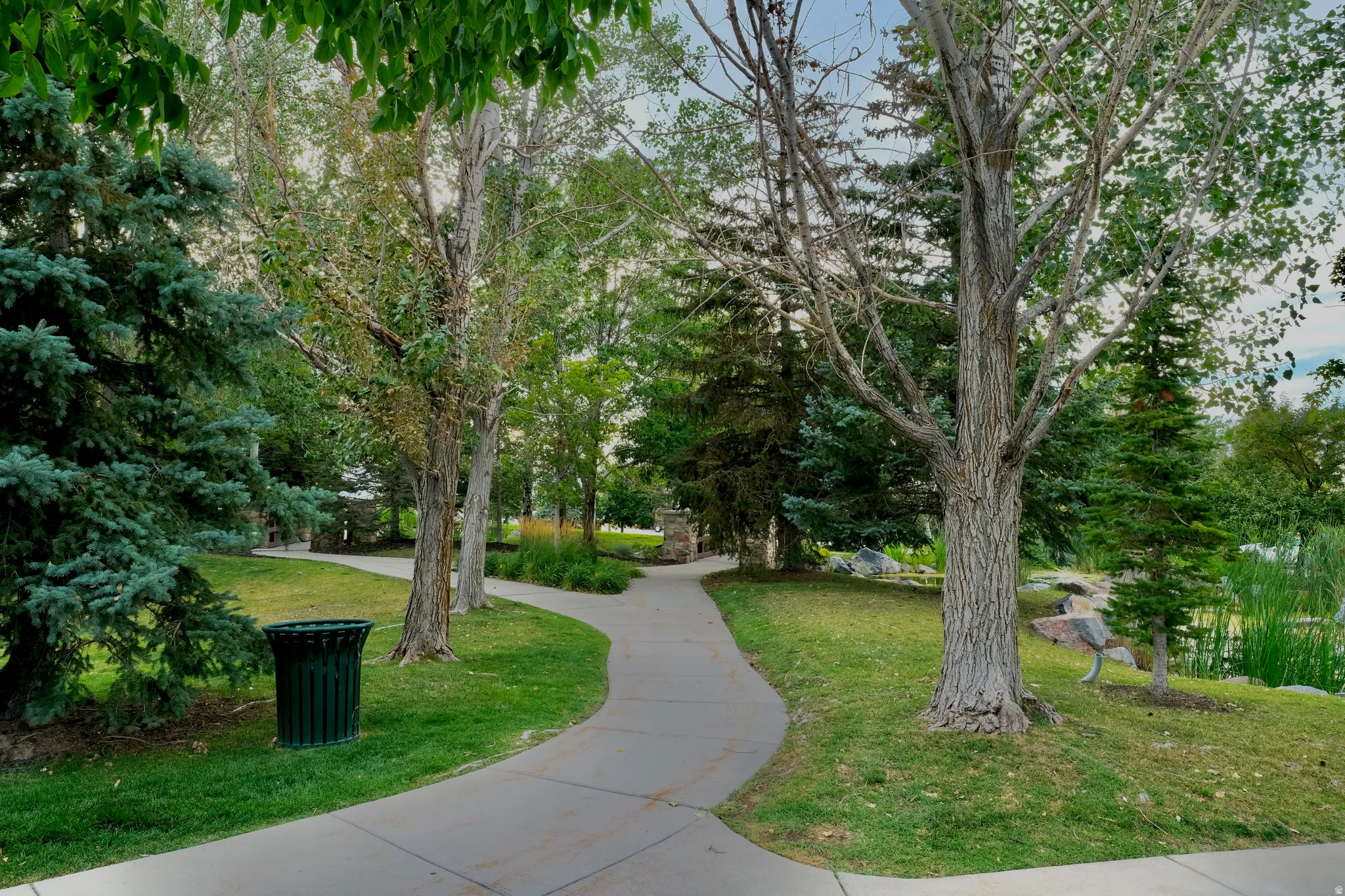 SunCrest community grounds featuring winding walkways, mature trees, open lawns for picnics and gathering, and landscaped green space used for farmers markets, outdoor concerts, and neighborhood events.