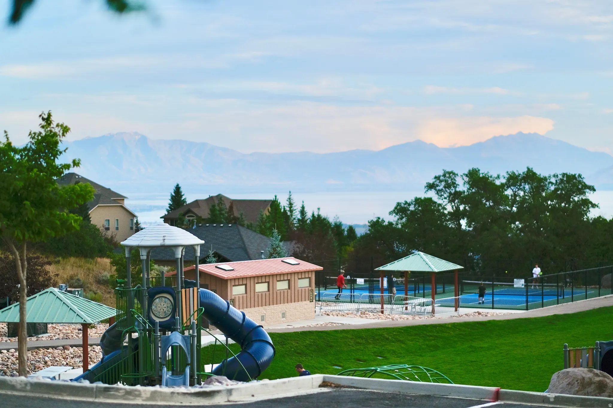 SunCrest Park overlooking Utah Lake, featuring expansive green space, a modern playground, pickleball courts and sweeping valley and mountain views.