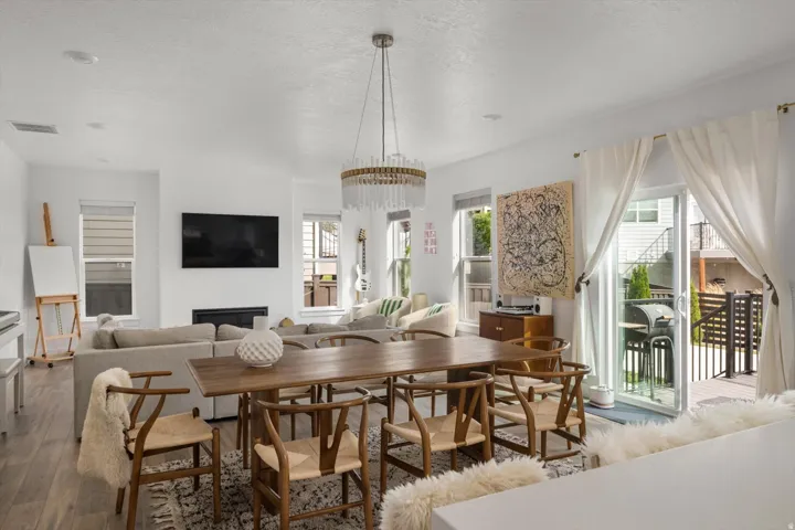 Open-concept living space with a dining area, a linear fireplace, and wood-finish flooring