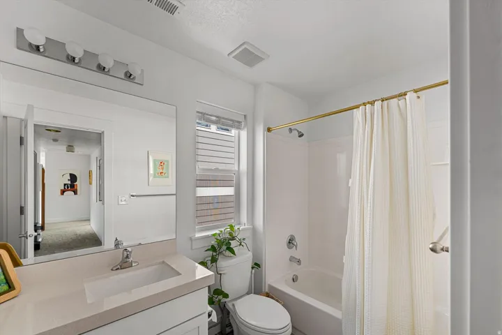 White vanity with an integrated rectangular sink, large frameless mirror, and a four-bulb vanity light fixture