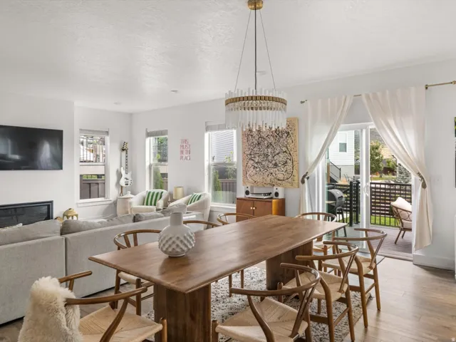 Open-concept living space featuring wood-finish flooring, a contemporary chandelier, a built-in fireplace, and sliding glass doors leading to an exterior balcony