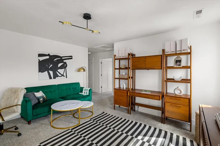 Recessed ceiling light fixture, wood-finish shelving unit, light gray carpet, and white walls