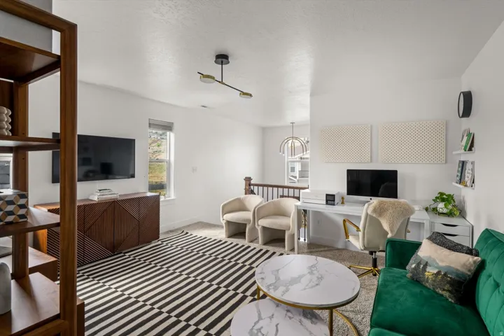 Carpeted flooring, contemporary light fixture, built-in shelving, white walls, and a window with natural light