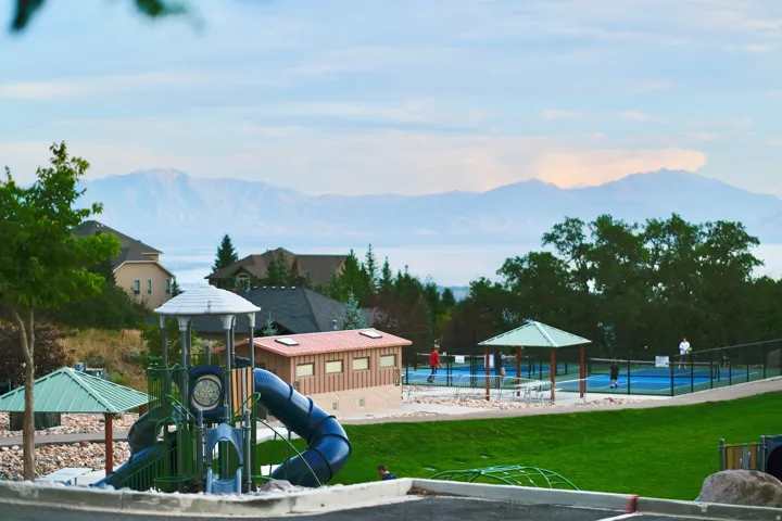 SunCrest Park overlooking Utah Lake, featuring expansive green space, a modern playground, pickleball courts and sweeping valley and mountain views.