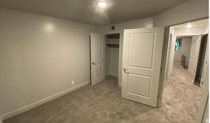 Wall-to-wall carpeting with light-toned walls and trim, featuring a built-in closet with shelving