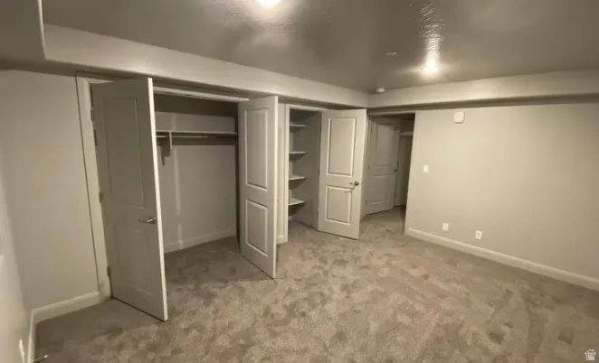 Light gray carpeted flooring, neutral wall paint, white trim, recessed lighting, and multiple closet storage options