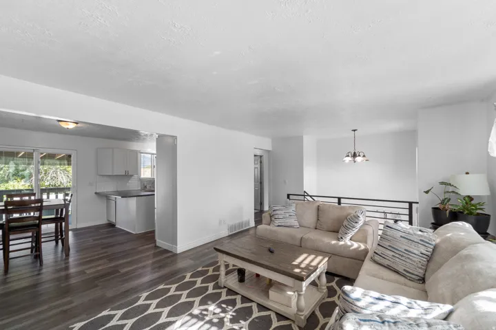 Wood-finish flooring, white cabinetry, subway tile backsplash, and a sliding glass door to the deck