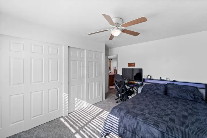 Recessed lighting, wood-finish ceiling fan, white wall paint, carpet flooring, and white paneled bi-fold closet doors