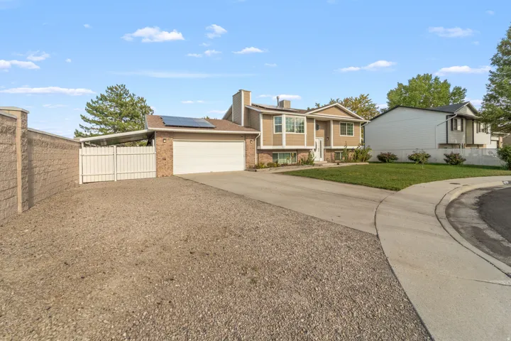 Split-level residence featuring a two-car garage, solar panels, a dedicated RV pad with gate, and a manicured front lawn