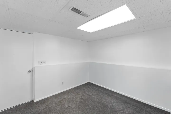 Finished room featuring drop ceiling, recessed lighting, and dark gray carpeting