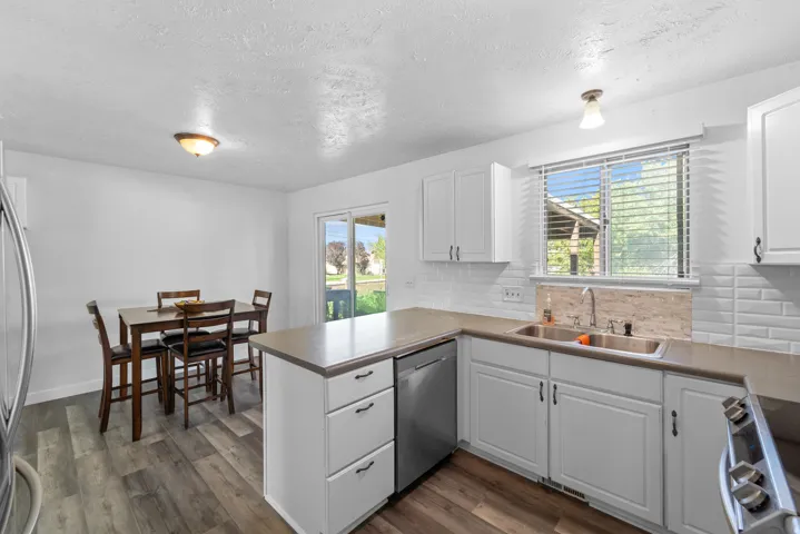 Bright, updated kitchen featuring white cabinetry, stainless steel appliances, subway tile backsplash, and wood-finish countertops with ample storage and workspace