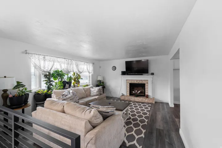 Spacious living area featuring wood-finish flooring, a fireplace with a tiled surround and white mantel, and multiple large windows