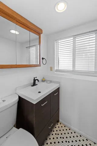 Bathroom featuring a single vanity with dark wood-finish cabinetry, white countertop, and black fixtures