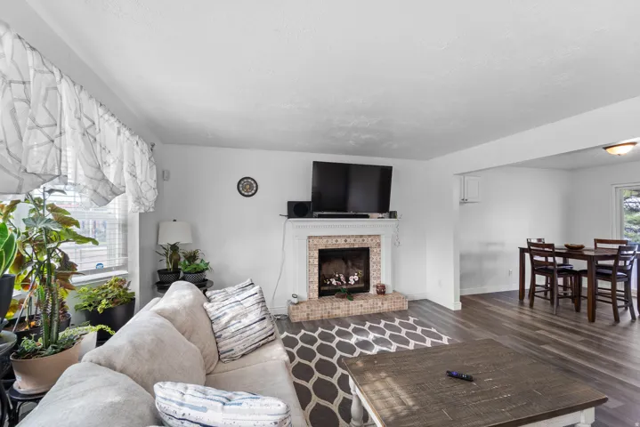 Living area featuring a fireplace with a decorative mantel and hearth, wood-finish flooring, and a window with blinds