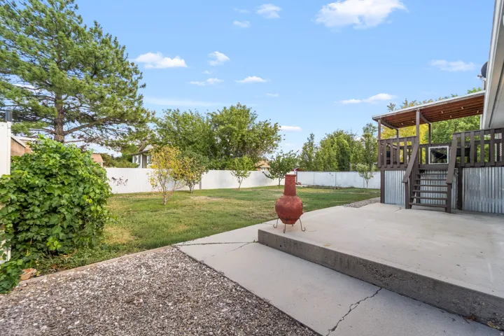 Expansive backyard featuring a manicured lawn, established trees, and a privacy fence