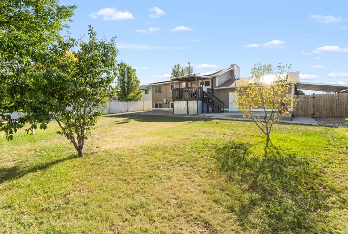 Expansive rear yard featuring mature trees, a multi-level deck, and a privacy fence