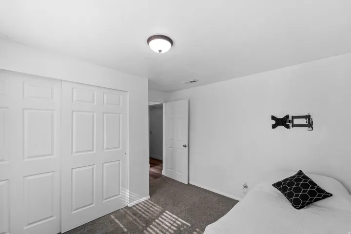 Recessed ceiling light fixture, bi-fold closet doors, wall-mounted television bracket, and carpet flooring
