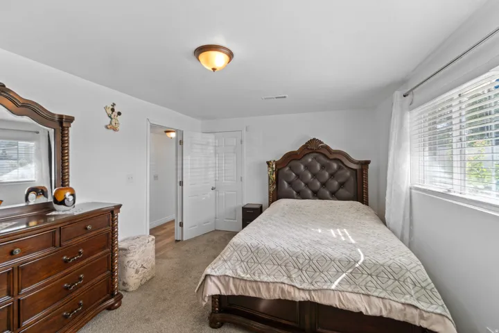 Carpeted flooring with white walls, a single window with horizontal blinds, and a flush-mount ceiling light fixture