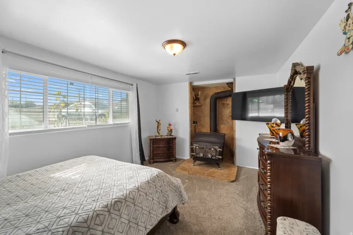 Wood-burning stove with a stone surround, integrated wall-mounted television, and a wide window with blinds