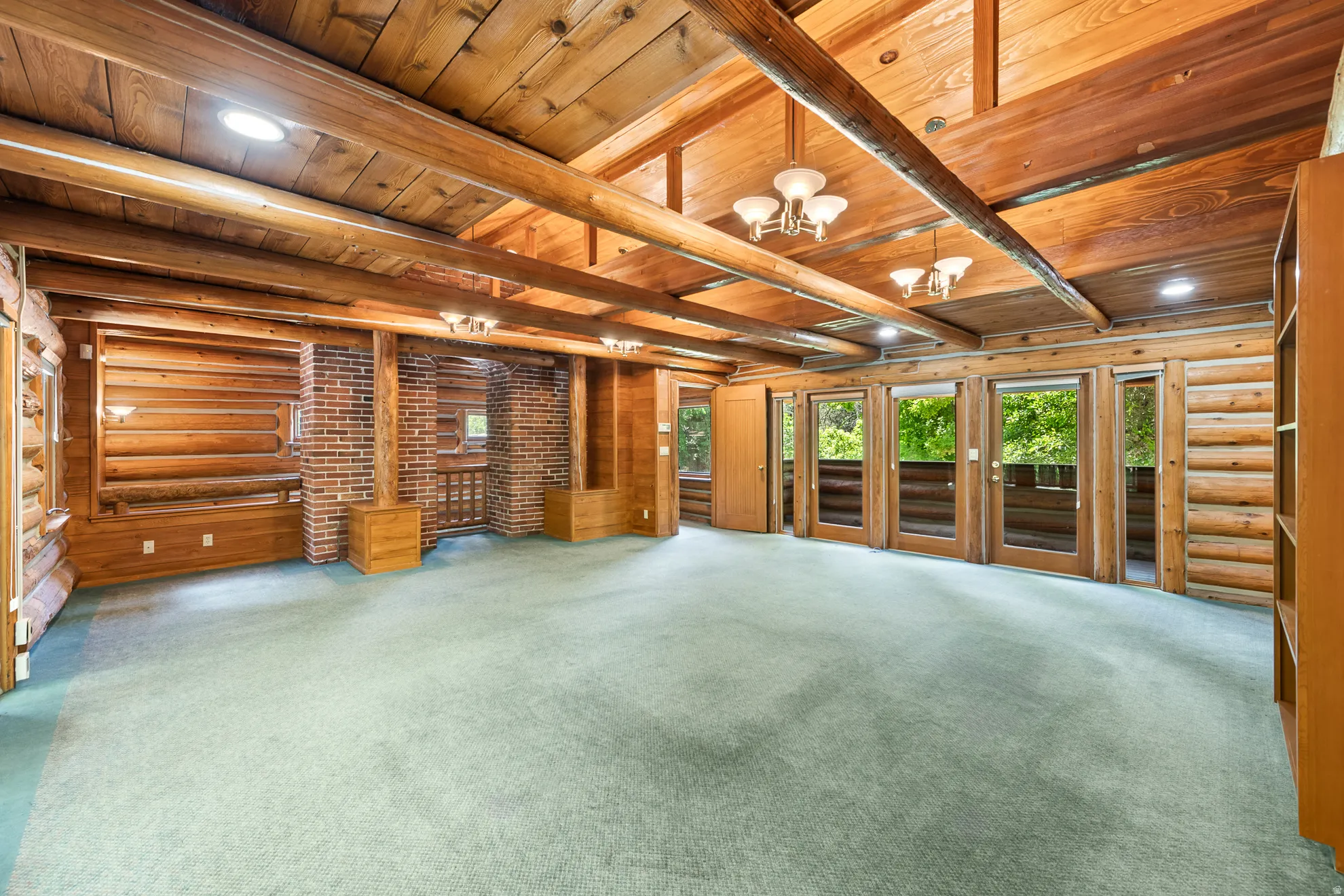 Vaulted wood-paneled ceilings with exposed beams, brick accents, and multiple glass-paned doors opening to an exterior balcony