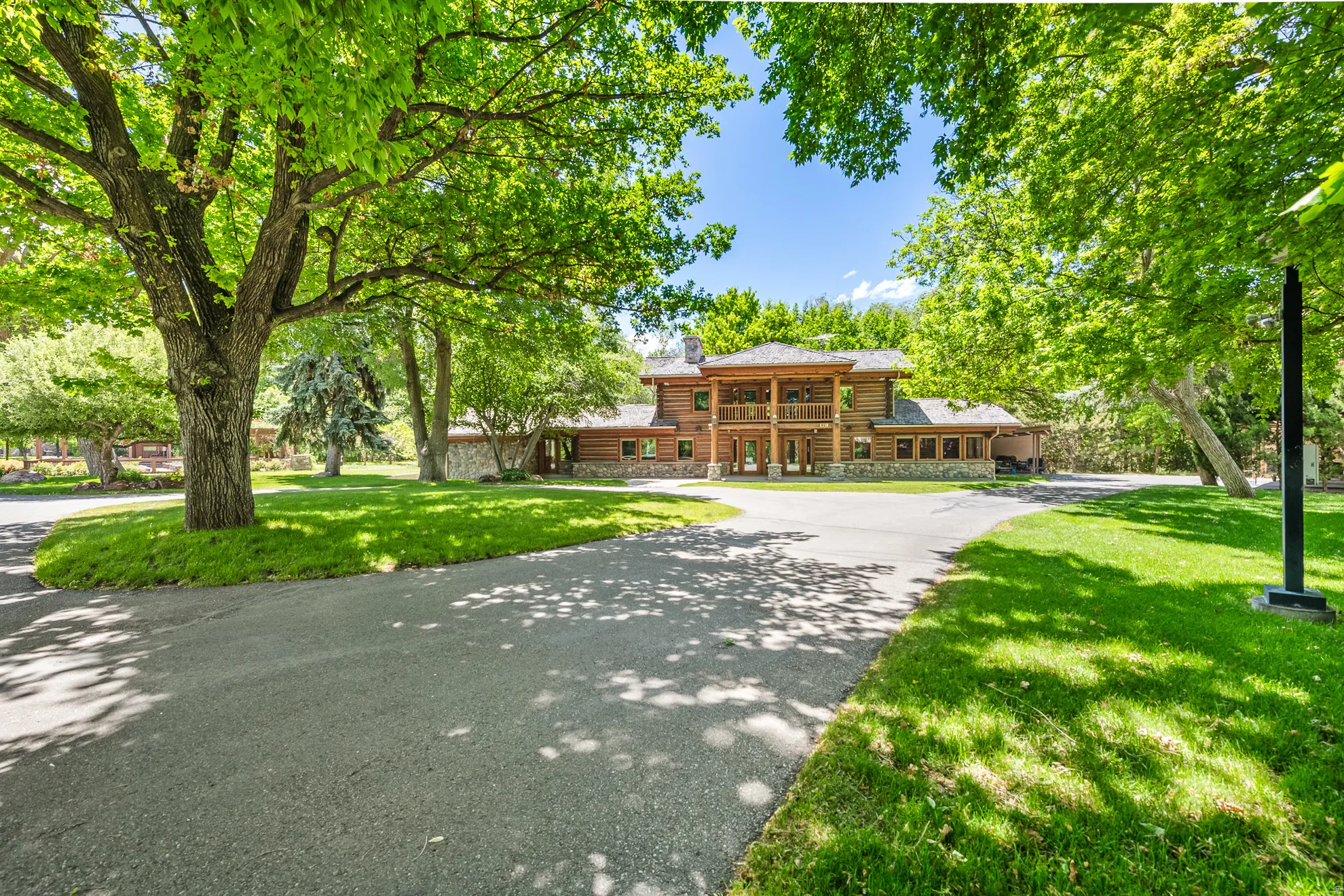Paved driveway leading to a log and stone exterior residence
