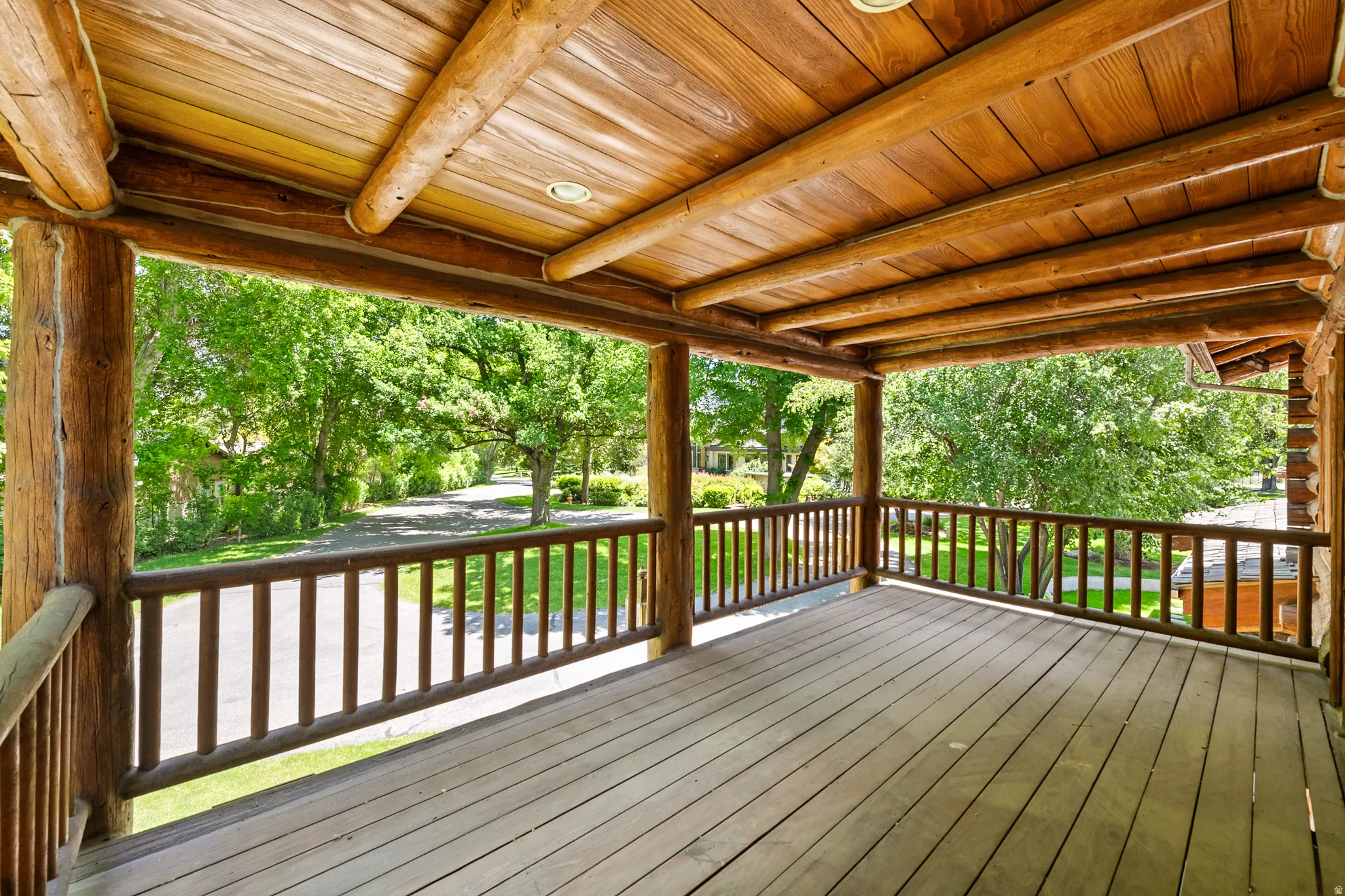 Covered porch featuring log construction, recessed lighting, and wood-finish flooring