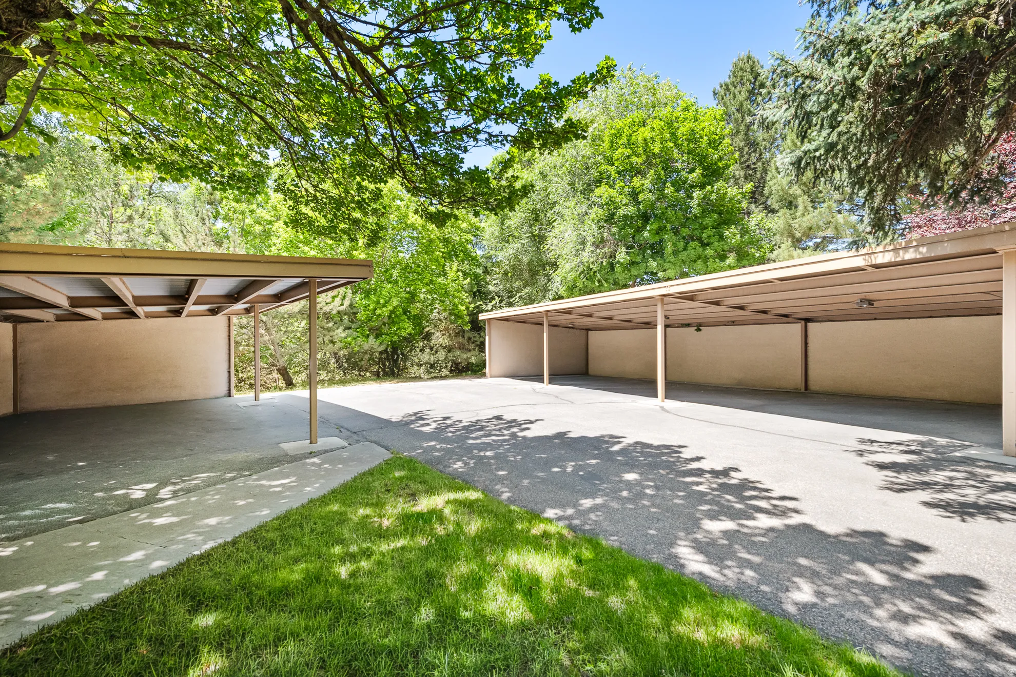Two tan-colored carports with concrete flooring provide covered parking