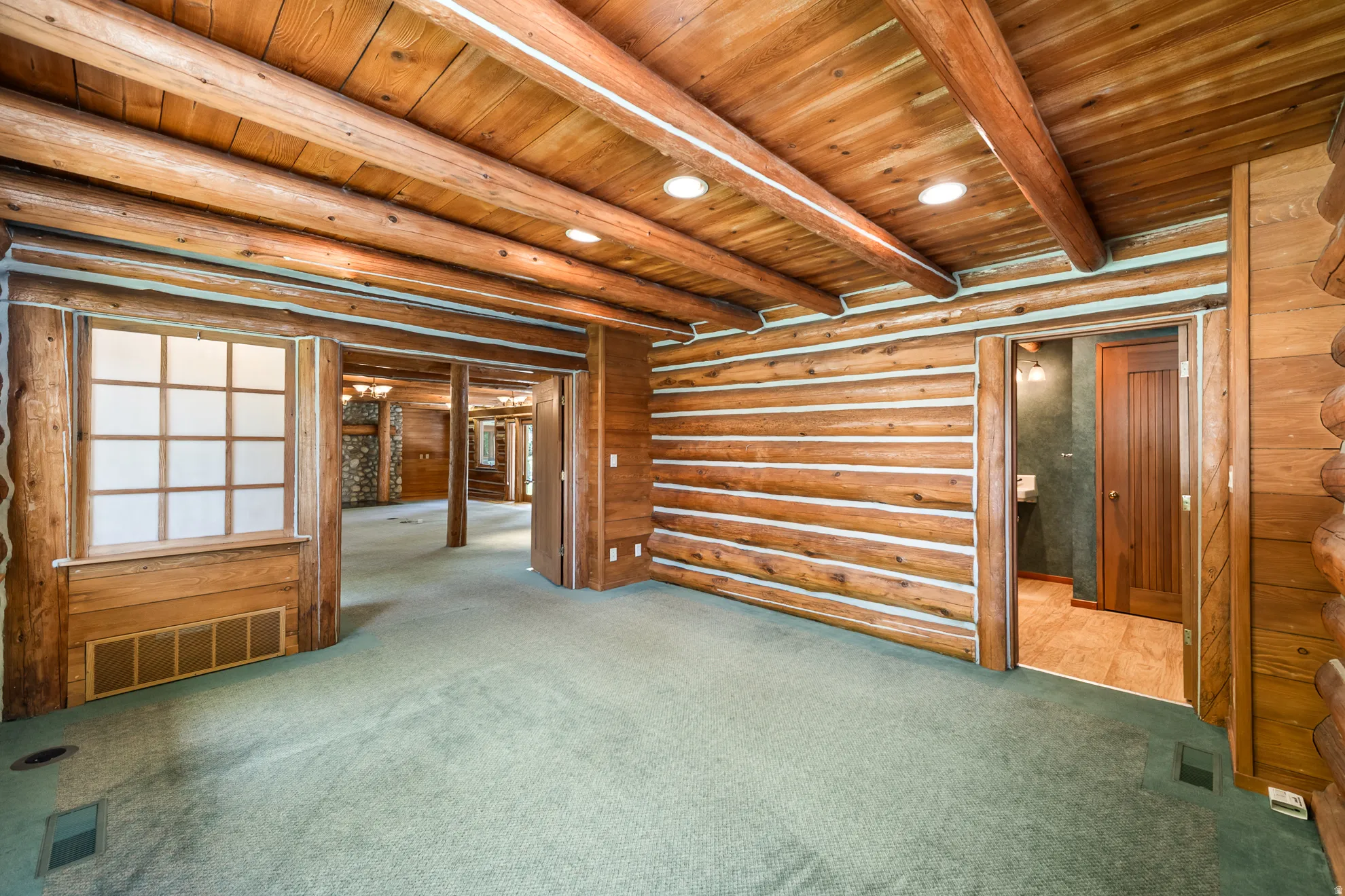 Interior space featuring robust log walls and exposed timber ceiling beams