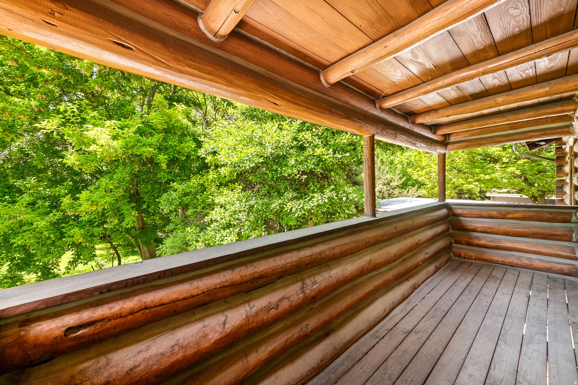 Wood-finish porch featuring exposed log construction, a wood plank floor, and a wood plank ceiling