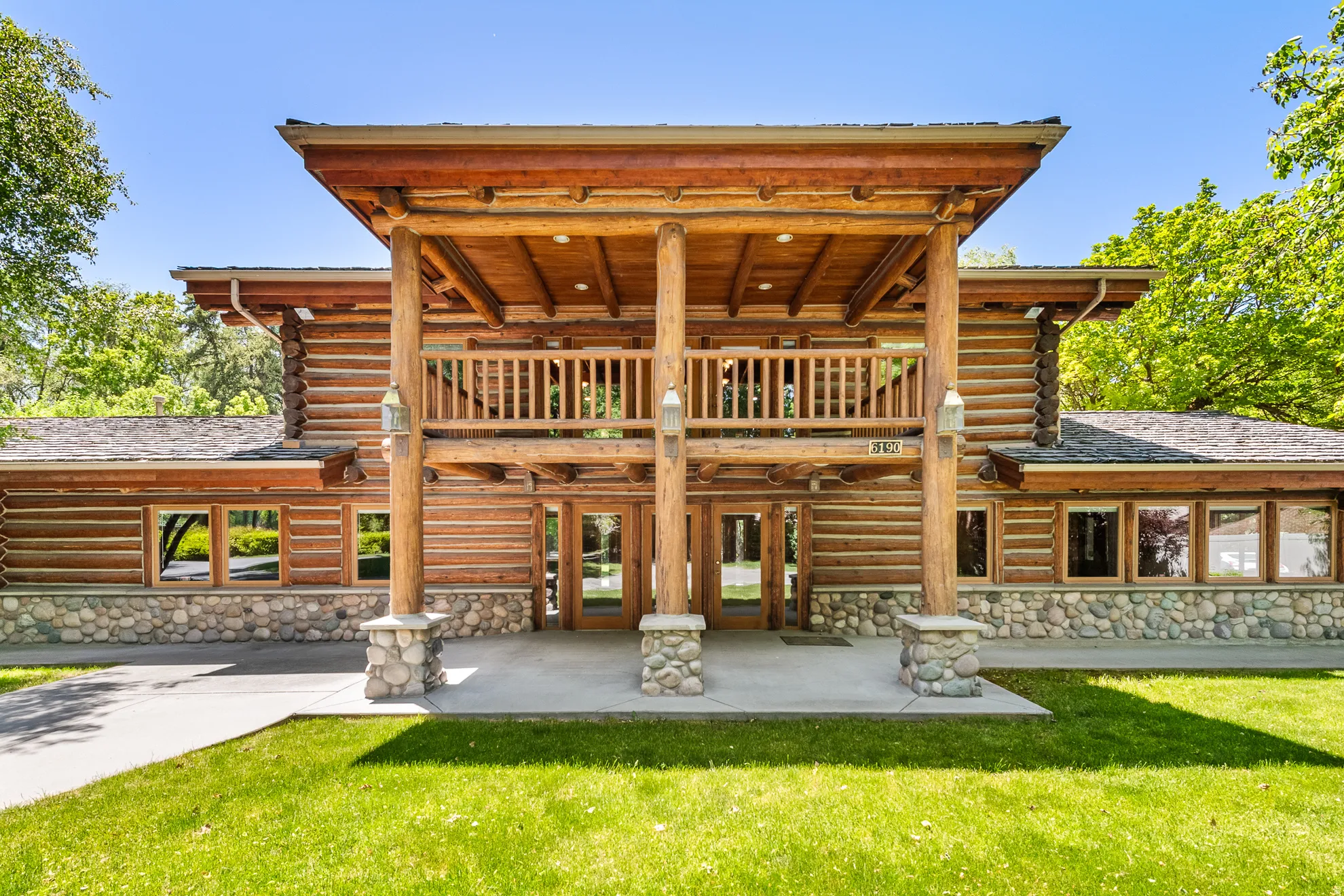 Log cabin exterior featuring a prominent two-story entry with a covered porch and second-story balcony