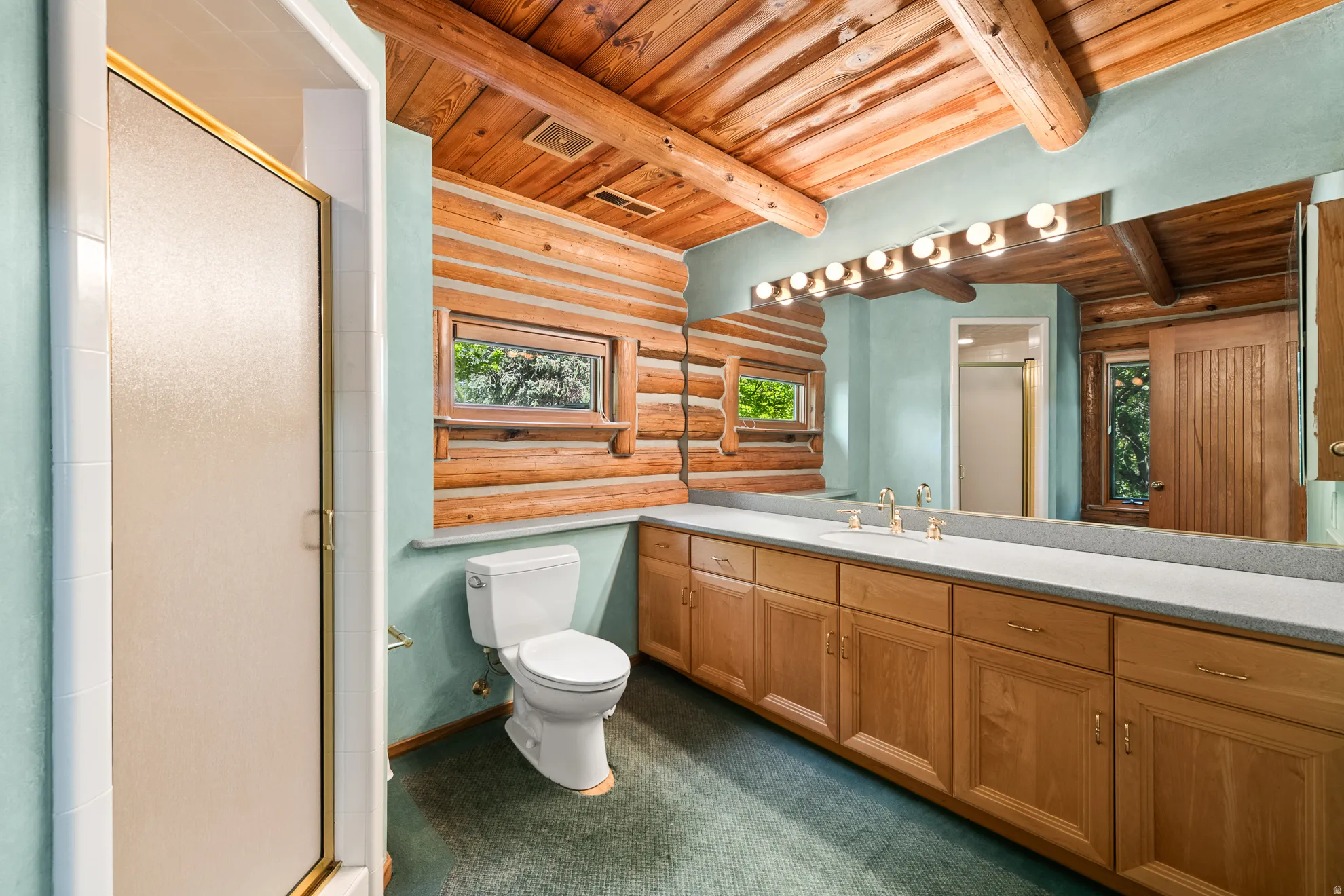 Bathroom featuring a spacious double vanity with extensive cabinetry, a full-width mirror, and two windows
