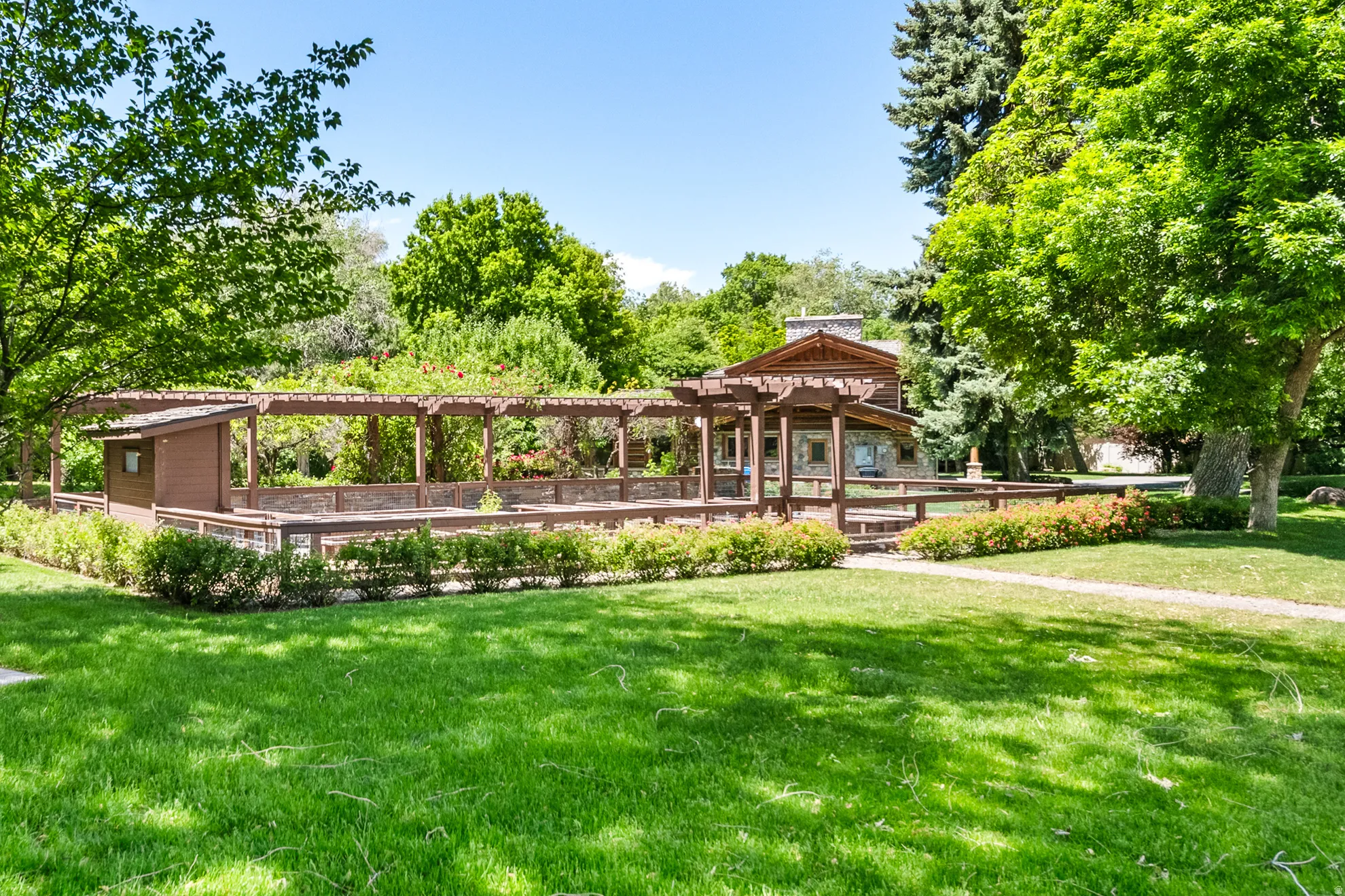 Expansive lawn featuring mature trees and a long wooden pergola structure