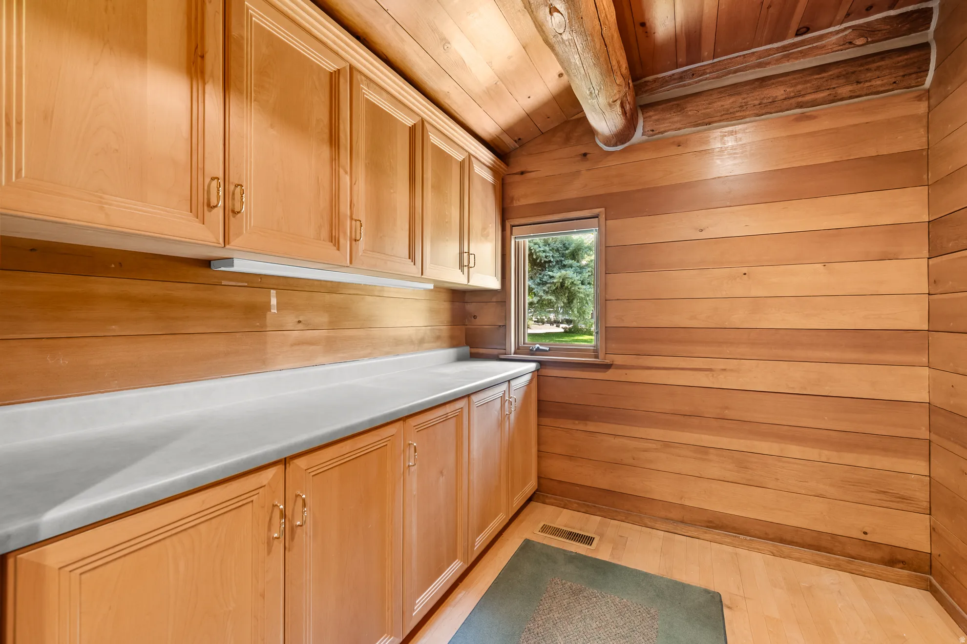 Built-in cabinetry with light-toned wood-finish doors, white countertops, and under-cabinet lighting