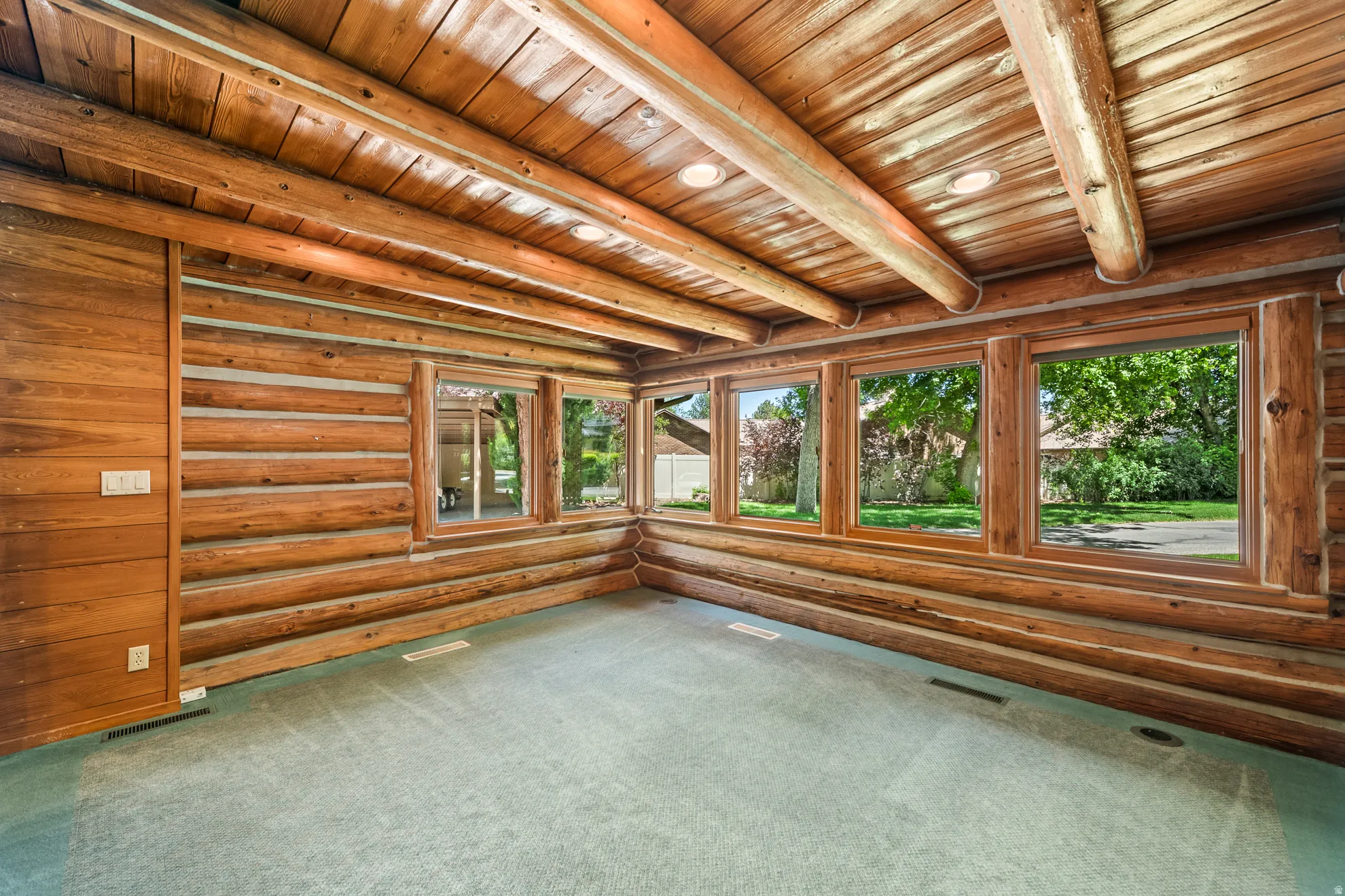 Expansive room featuring log walls and ceiling beams