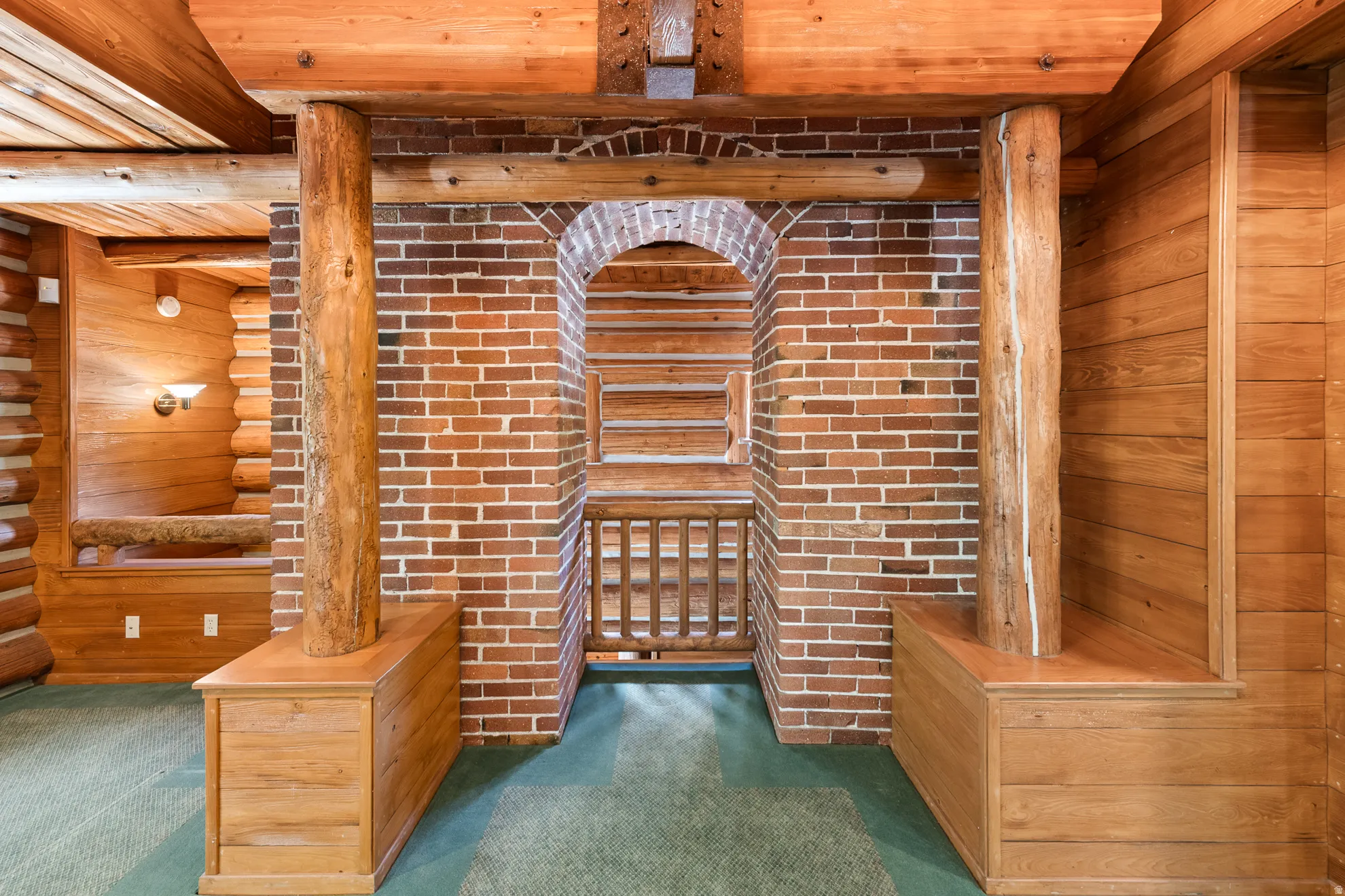 Brick archway with wood railing, flanked by robust wood columns