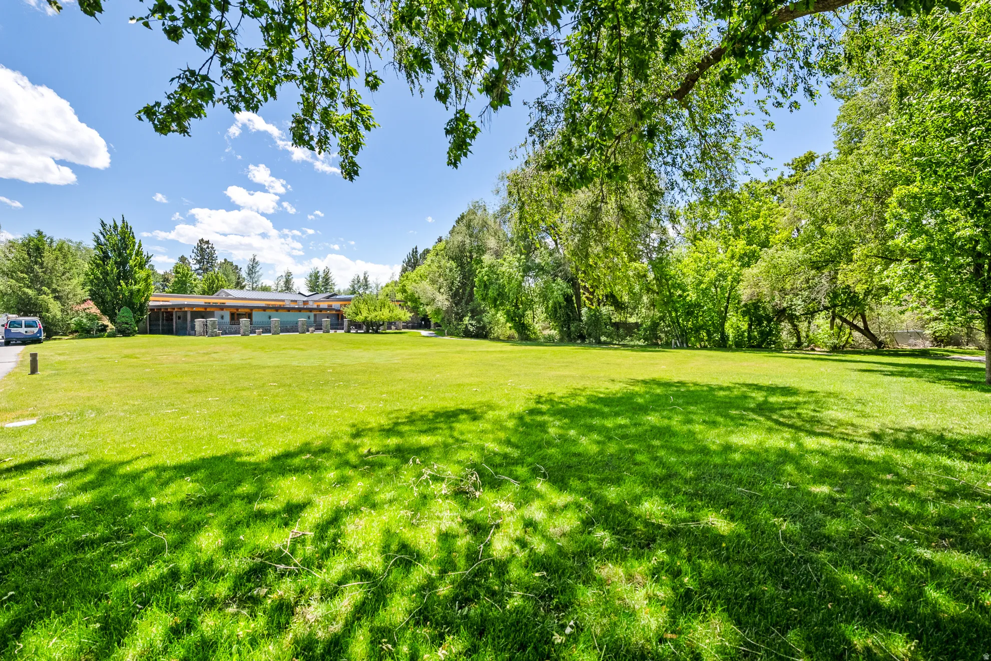 Expansive green lawn with mature perimeter trees, providing natural shade