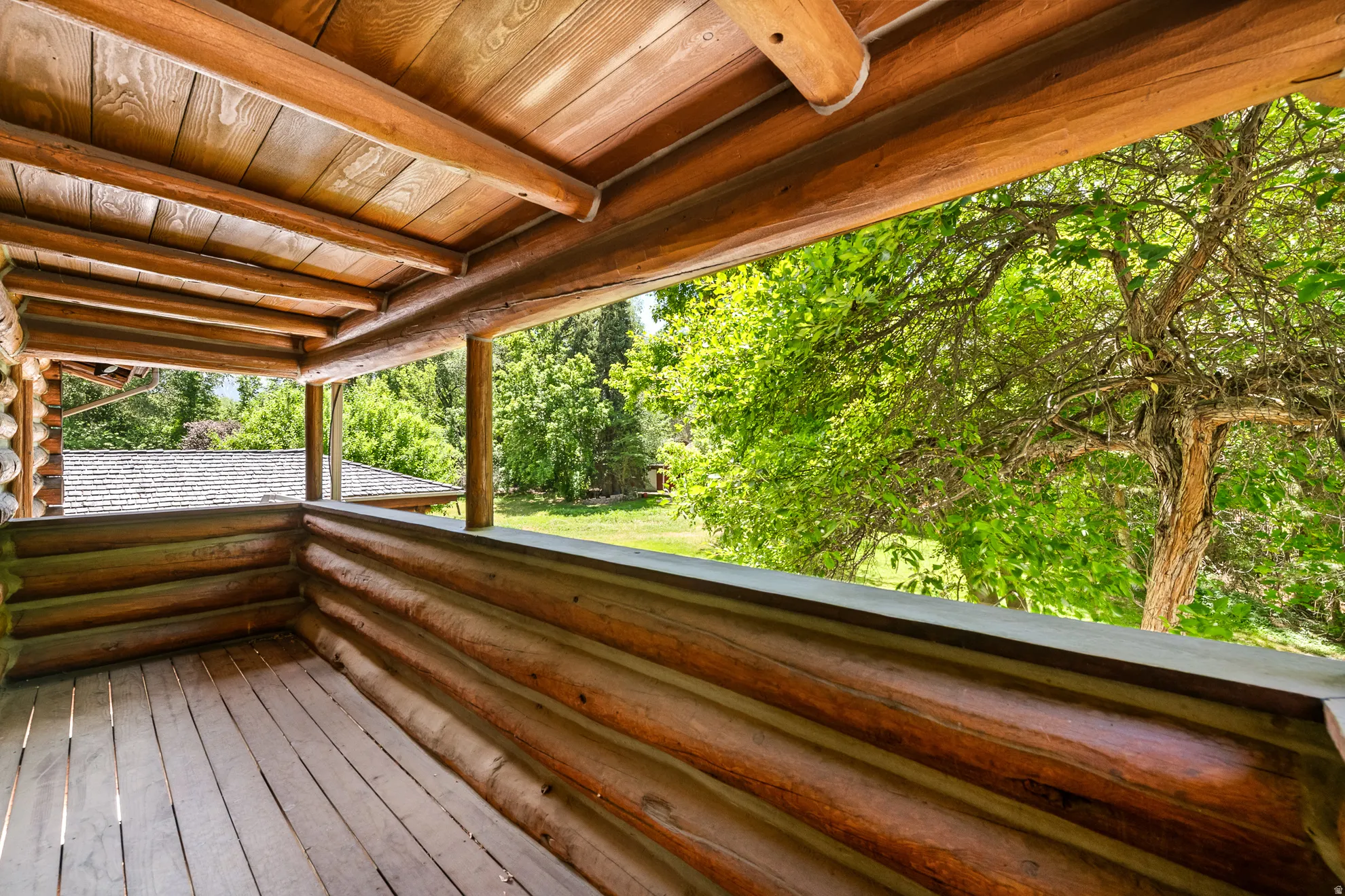 Rustic log-cabin style porch featuring a wood-plank floor, log walls, and a wood-paneled ceiling