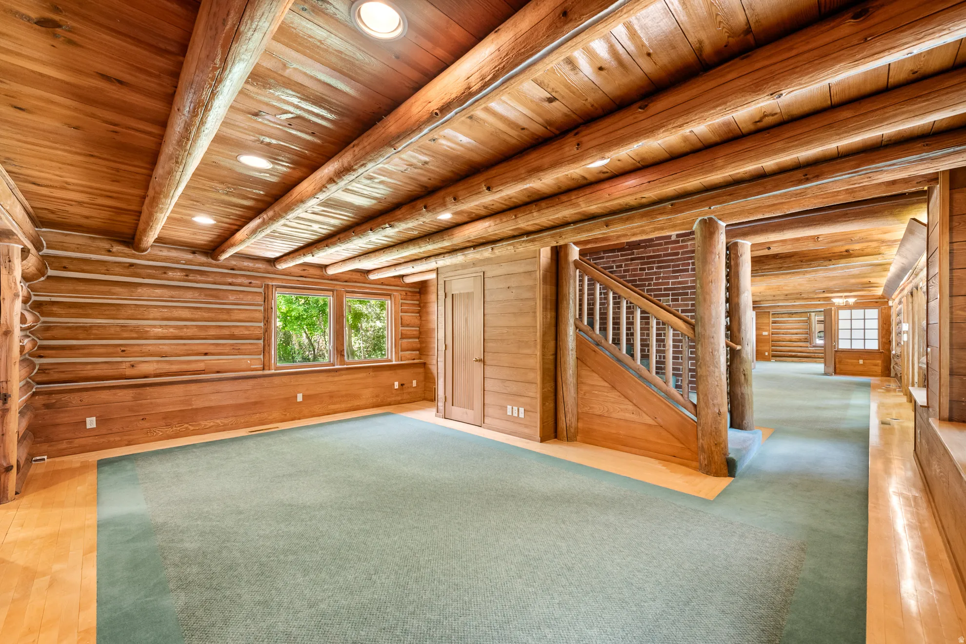 Spacious room featuring log-style walls and exposed log beams