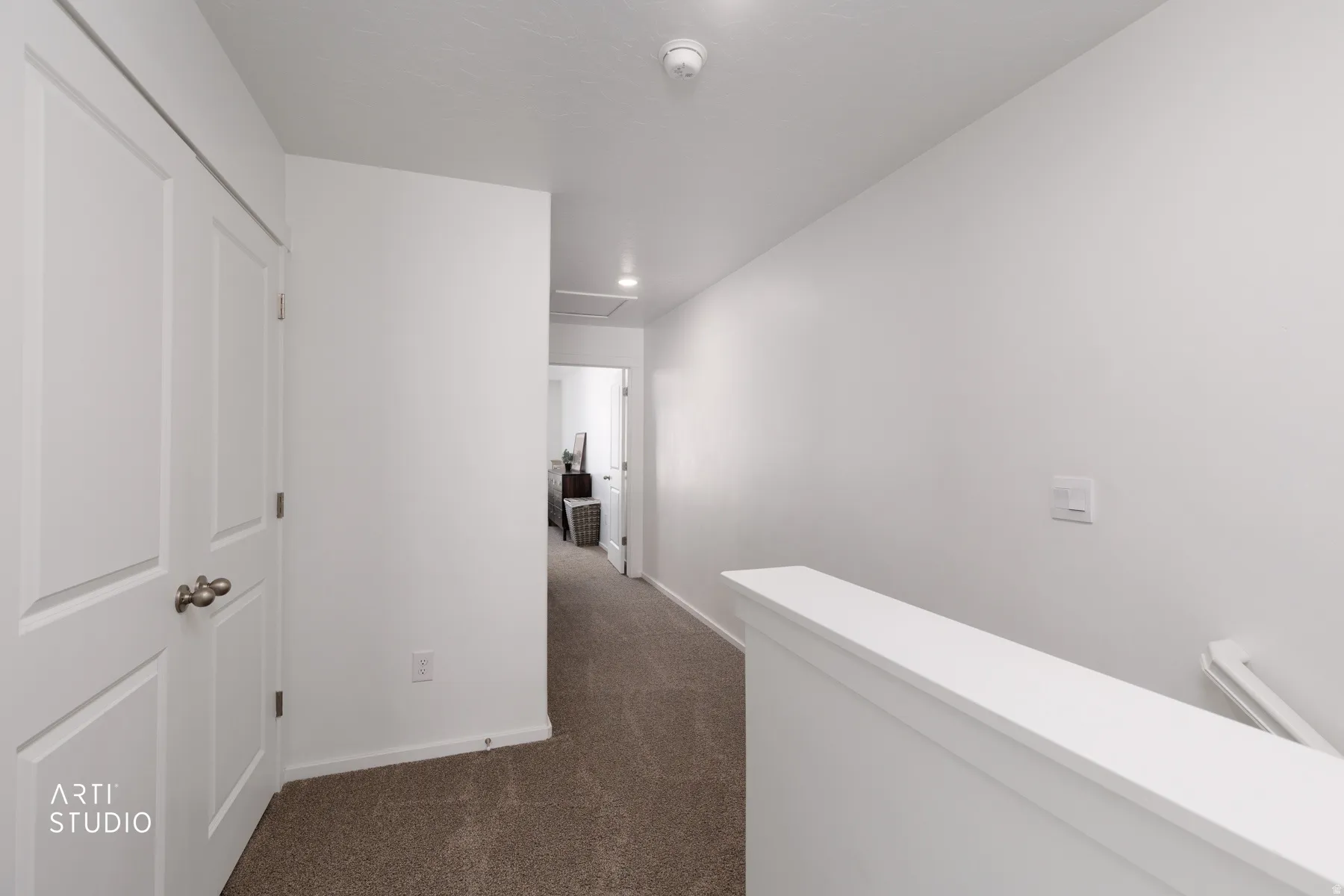 Carpeted hallway with white walls and a white painted banister