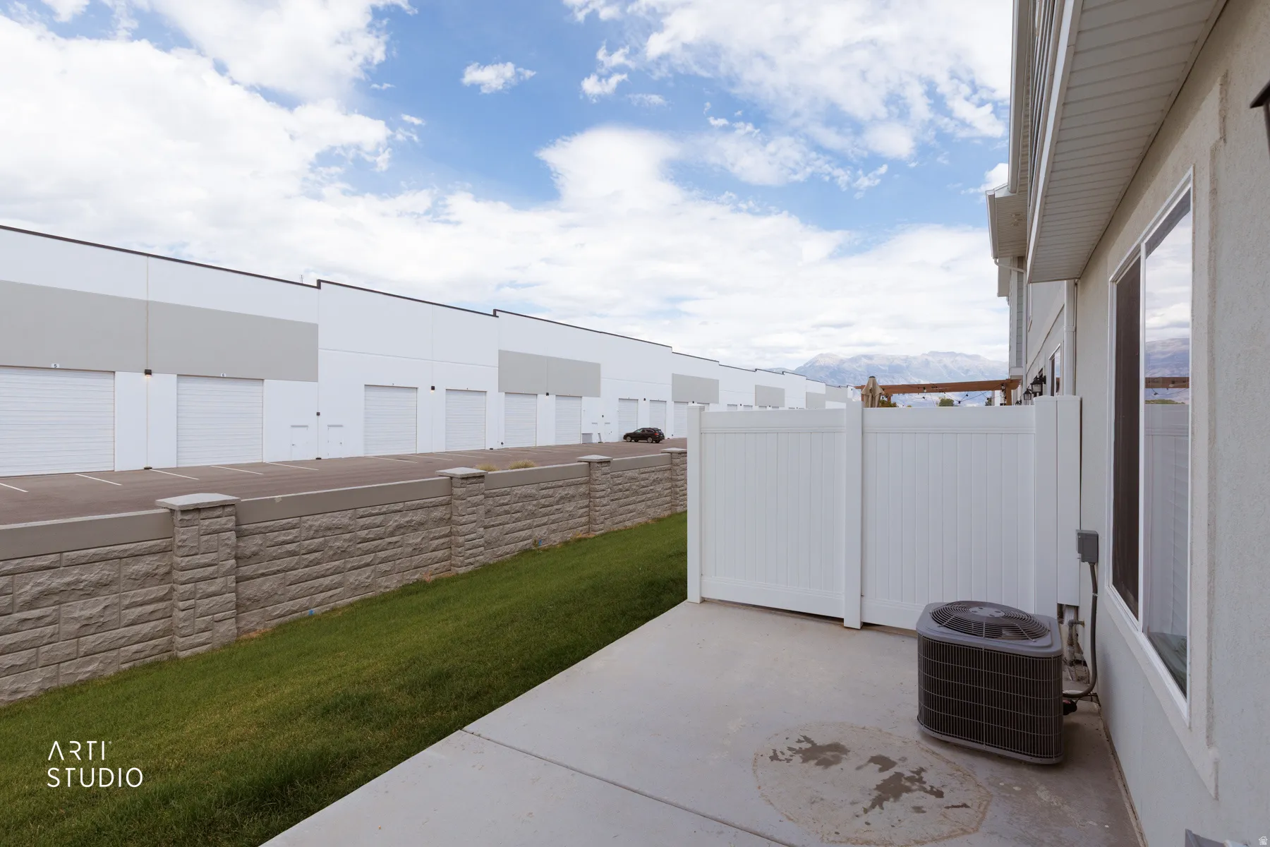 Private concrete patio with white privacy fencing and landscaped grass area