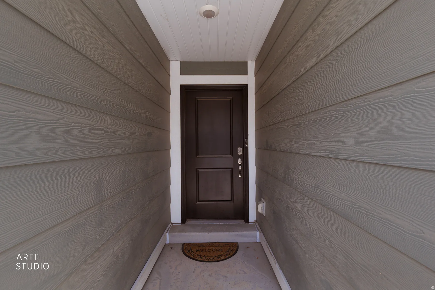 Entryway featuring a dark paneled door, white trim, and light-toned siding