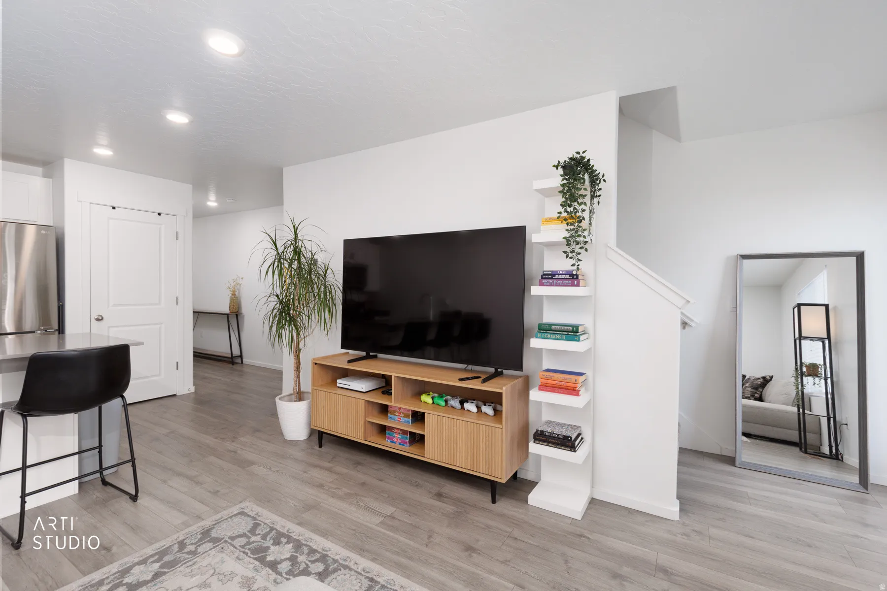 Recessed lighting, wood-finish flooring, stainless steel refrigerator, white interior walls, and built-in shelving